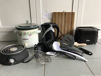 Overview of all appliances and utensils including slow cooker, kettle, toaster, burner, cutting board and utensils