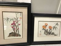 Pair of framed watercolor paintings featuring Asian floral themes, one vertical and one horizontal.