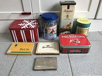 Photo showing full set of vintage collectible tins including Tim Hortons, Ballantine's whisky, festive red snowflake tin, Mackintosh's toffee, Gold Medal and cigarette tins Black Cat and Chesterfield plus metal cigarette case.