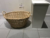 Wicker basket and tall white container side by side on tiled floor for size and appearance reference.