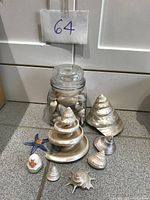 Full view of collection on floor with shells arranged in front of glass jar containing small shells, also small rubber duck and rubber starfish visible