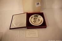 Photo of the plate displayed in velvet-lined original red box with certificate of authenticity visible.