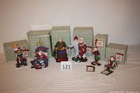 Six Dept 56 Christmas figurines lined up in front of original boxes featuring Christmas Eve family members.