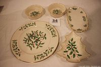 Top view of the complete Lenox Holly Berry porcelain serving set showing platter, elongated dish, tree candy dish, and two sauce bowls with gold edges and holly berry design.
