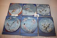 Six collector plates in original boxes showing nature scenes with birds and festive themes, arranged in two rows of three.