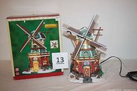 Front view of the Lemax ceramic Stony Brook Windmill with rotating blades and lit windows next to its original box