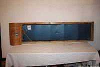 Full top view of the wooden toboggan showing the blue padded seat area and the wood construction with steam bent front hood, and attached yellow rope.