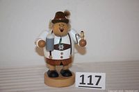 Front view of the wooden German smoker figurine showing the figure holding a beer mug in one hand and a pipe in the other, wearing traditional lederhosen and hat.