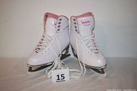 Front view of white figure skates size 8 with blades and laces placed in front.