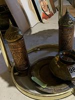 Photo showing the two tall copper and brass candleholders with perforated brass tops, the engraved brass pedestal bowl and two brass trays beneath.