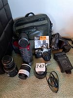 Full lot displaying the camera, four lenses, carrying bag, instruction booklet, two leather cases, external flash, and accessories all laid out on carpeted floor.