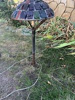 Full view of the iron outdoor lamp showing the glass mosaic lampshade and iron pole.