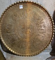 Front view of circular brass tray showing full engraving and scalloped rim