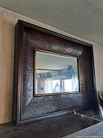 Full side angle showing the framed mirror with embossed floral metalwork and beveled glass.
