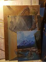 Three original paintings stacked, showing parts of deer and mountain landscapes.