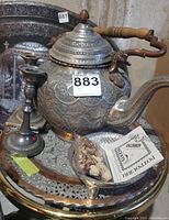 Wide angle image of the kettle, candlestick holders, potpourri bowl and trays grouped together showing the engraving and textures on each item.