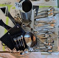 Top view of various stainless steel kitchen items and cutlery arranged on a table.