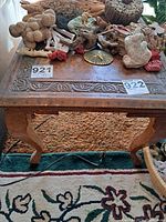 Overall front view of the wooden side table showing intricate inlay on the top surface, the curved leg, and some items on the table (not included in the lot).