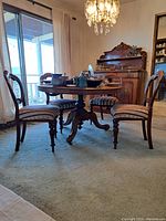 Wide angle shot of vintage round wooden pedestal table and four matching balloon back chairs in room setting