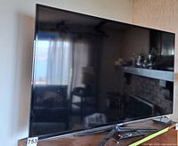 Samsung 55 inch flat screen TV on wooden surface showing overall product and stand.