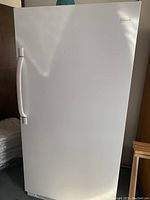 Exterior front view of white Frigidaire upright freezer with closed door.