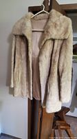 Vintage vintage ladies fur coat hanging on a hanger, shown front and side views.