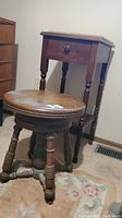 Photo of the vintage wooden night table and wooden piano stool side by side on carpeted floor, showing their overall shape and style.