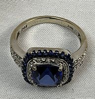 Top-down view showing cushion-cut blue center stone, inner white and outer blue halo, split shank