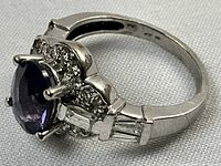 Close-up angled view showing oval amethyst and surrounding round diamonds with baguette diamond accents