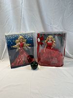 Two boxed Barbie dolls from 2017 and 2018 displayed with a size reference green apple in front, showing the scale and condition of the boxes and dolls.