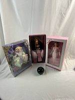 Three mint in box Barbie dolls displayed together with a small green apple for size reference