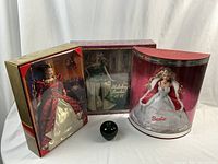 Three packaged Holiday Barbies together with black apple for scale