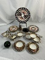 Overall view of all Imari china pieces and silver servingware on white backdrop