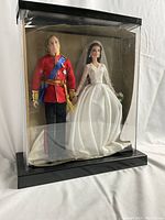 Front view of both dolls inside clear dome case with black base