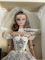Close-up of doll’s face, tiara and veil inside box