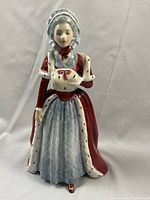 Porcelain figurine showing full front view of Countess Spencer in red and blue dress with fur trim and bonnet, holding white muff.