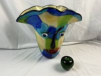 Front view of multicolor glass vase with face and green glass apple for scale