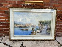 Framed painting showing full coastal landscape scene under glass