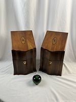 Pair of mahogany cutlery boxes with serpentine fronts and inlaid medallion lids shown closed alongside a green apple for size reference.