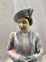 Close-up of the porcelain figurine showing detailed face, hat, pastel clothing and pearl necklace