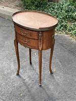 Front-left three-quarter view of oval side table showing wood veneer and gallery rail