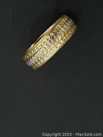 Close-up photo of the textured gold ring showing detailed pattern and band thickness