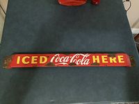 Full view of the vintage Coca Cola porcelain push bar showing text and rust spots.