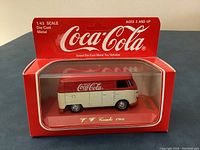 Front and side view of the Coca-Cola branded 1/43 scale diecast Volkswagen van in original box.
