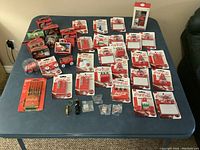 Top-down view of entire collection spread on table with all items clearly visible, showcasing diverse Coca-Cola collectible items like magnets, trucks, pens, and tins.