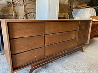 Full side view showing six drawers, warm wood finish, and visible wear on lower foot area.