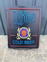 Front view of the Miller Lite beer neon sign showing blue neon text 'Lite Cold Beer' and red neon frame with central logo