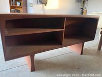 Side view of the wooden sideboard showing open shelving compartments and legs.