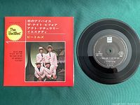 Photo of front side of The Beatles Japan EP 45 RPM record and sleeve with Japanese text and Beatles in striped costumes.
