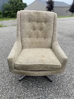 Front view of beige upholstered swivel chair showing tufted backrest and seat cushion.